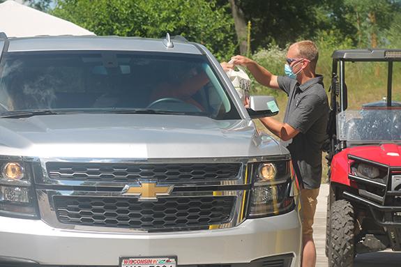 Saxeville-Springwater Fire Chief, Alex Peterson, gives Marv Hazlett some chicken dinners by way of drive-through service during the July 12 chicken barbeque.
