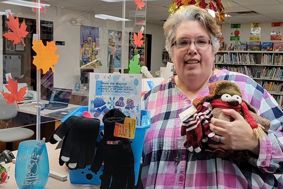 Deb Sadowski, with Pete the Penguin, encourage patrons to bring in scarves, hats and gloves for the SOS program. 