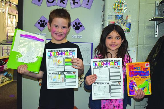 Riverview Elementary Kindergartener Jude McEwan and First Grader Aubree Meyer show off the Determination Goal Sheets they created. Earlier this year, students and staff members were encouraged to come up with school and home determination goals and track their progress. 
