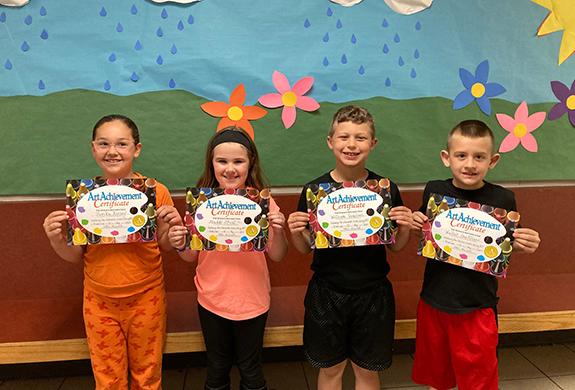 Riverview First Graders Jerika Rooney, Maddy Stock, William Vaughan, and Walter San Filippo show off their Character Award they were presented during the school wide assembly on June 1. Select students from Riverview Elementary, Redgranite Elementary and Parkside School were selected to receive this award based on the character they used within the art room during the entire school year.