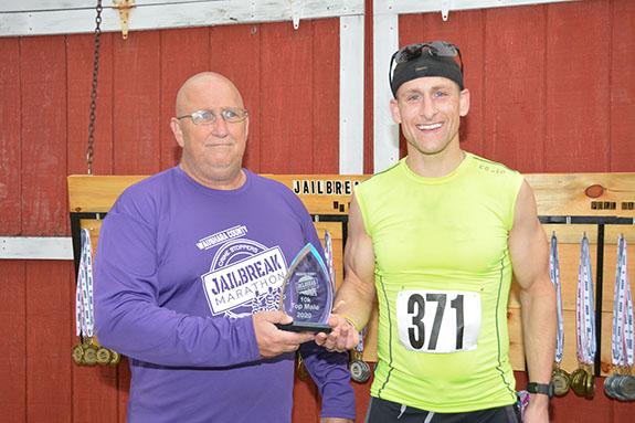 Jailbreak Marathon Race Director, Norm Duesterhoeft, presented Brad Gast, the overall winner in the 10K Run a trophy.