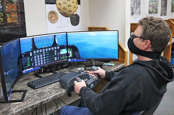 Preston de Bolt demonstrated the new flight simulator at the library. The system allows you to fly a plane virtually. It includes foot pedals and a steering wheel. The program is proving to be pretty accurate for a computer system.