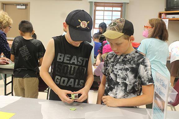 Levi Jalensky and Parker Brier cut out clay salmon during a July 12 presentation by Joan Voigt of the Wild Rose Fish Hatchery as part of the summer reading program at the Patterson Memorial Library in Wild Rose. 