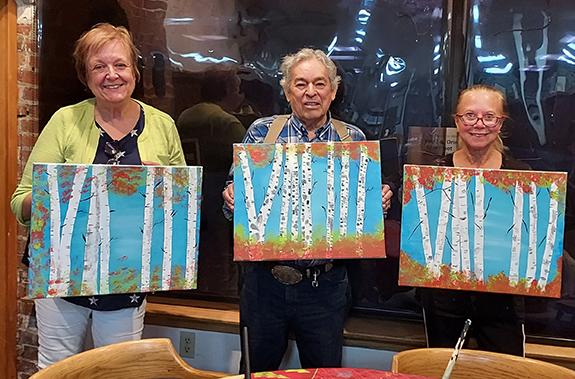 Painting sessions continue on Thursdays at the Hancock Public Library. Marilyn Hutkowski, Ed Villarreal and Twila Bergeron show off their birch tree photo that they painting on Aug. 25. 