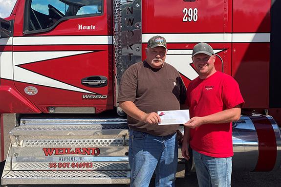 Howie Siegle receives his 25 years of service check from Weiland Trucking Vice-President, Brent Weiland.