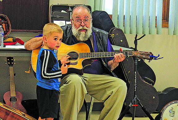 Three-year-old Jaxson Caves of Wild Rose was the only one choosing to strum Rich Bauman’s guitar with him holding it at the summer reading program entertainment held at the Patterson Memorial Library in Wild Rose on July 13. 