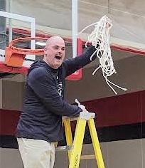 Almond-Bancroft boys’ basketball Head Coach Curt Lamb takes a cut off of the winning net. 
